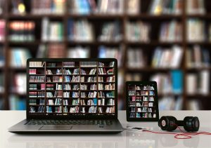 image showing laptop and tablet with photograph of books on shelfs on the screen