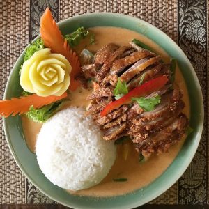 A chicken and rice meal is beautifully arranged on a plate." title="A chicken and rice meal is beautifully arranged on a plate.