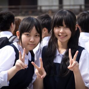 Two Japanese school girls smile and flash a typical "V-sign" as the pose for a photo." title="Two Japanese school girls smile and flash a typical "V-sign" as the pose for a photo.