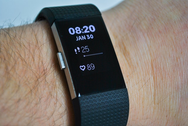 Photo of a Fitbit Charge HR on a person's wrist displaying time, steps taken, and heart rate.