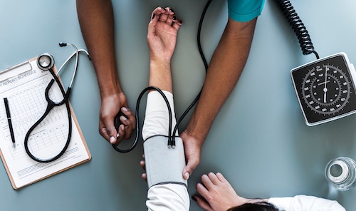 An arm in a blood pressure cuff and a medical chart