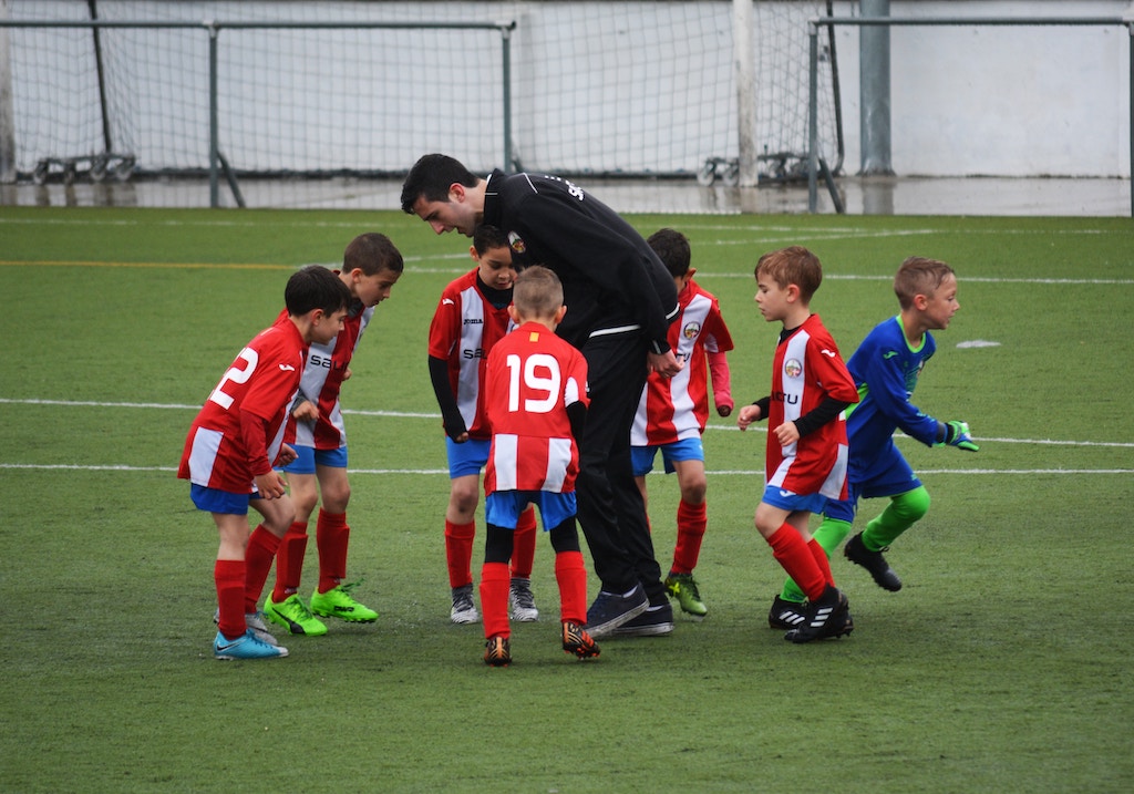 Children on a soccer field with their coach