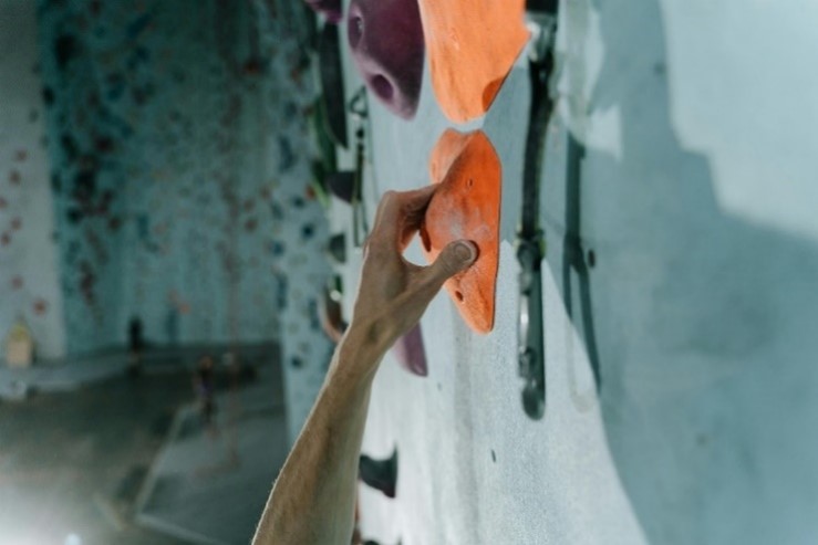 A hand grasps at a grip on a climbing wall.