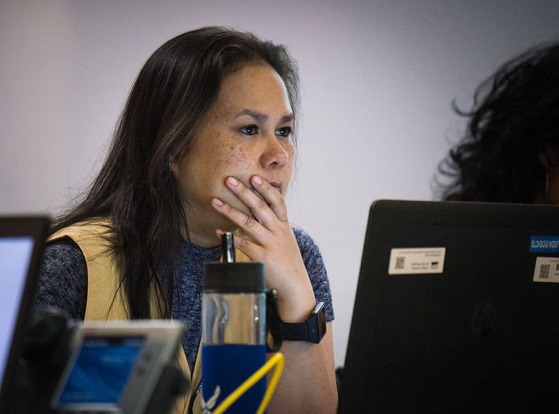 A women appears deep in thought while looking at a computer screen.