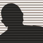 a person in silhouette behind blinds