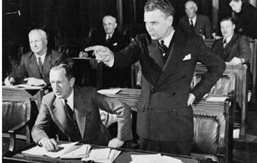 MP John G. Diefenbaker standing and pointing as he speaks in the House of Commons.