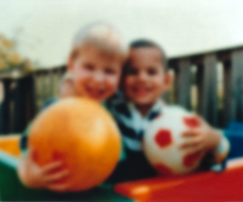 “Eye disease simulation, cataract.jpg” by National Eye Institute, National Institutes of Health is in the Public Domain Photo of two young children, blurred to simulate vision with cataracts