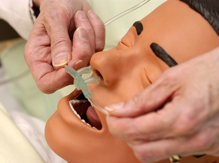 “Image00011.jpg” by British Columbia Institute of Technology (BCIT) is licensed under CC BY 4.0. Access for free at https://opentextbc.ca/clinicalskills/chapter/5-5-oxygen-therapy-systems/ Photo showing the insertion of a nasal cannula on simulated patient