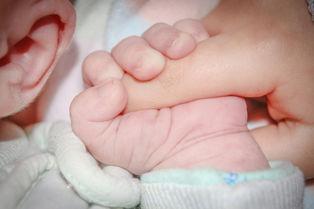 “baby-428395_960_720.jpg” by jarmoluk is licensed under CC0 Photo of an infant grasping an person's fingers