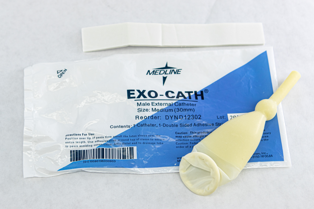 ”Male External Cath 1 .jpg” by Deanna Hoyord, Chippewa Valley Technical College is licensed under CC BY 4.0 Photo showing condom catheter lying on its packaging
