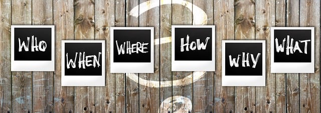 Signs on fence with the words Who, When, Where, How, Why, What.