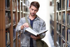 student looking at a book in a library